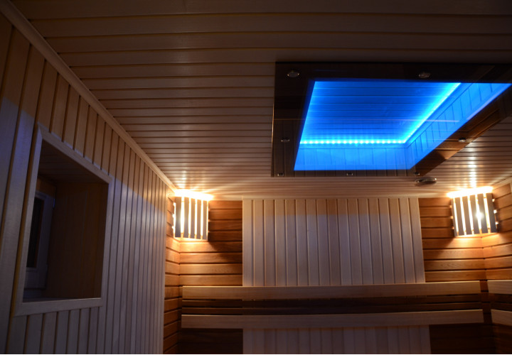 Sauna con estufa de leña y techo de cristal