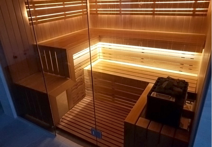 Sauna con fachada de cristal y vistas a la piscina.