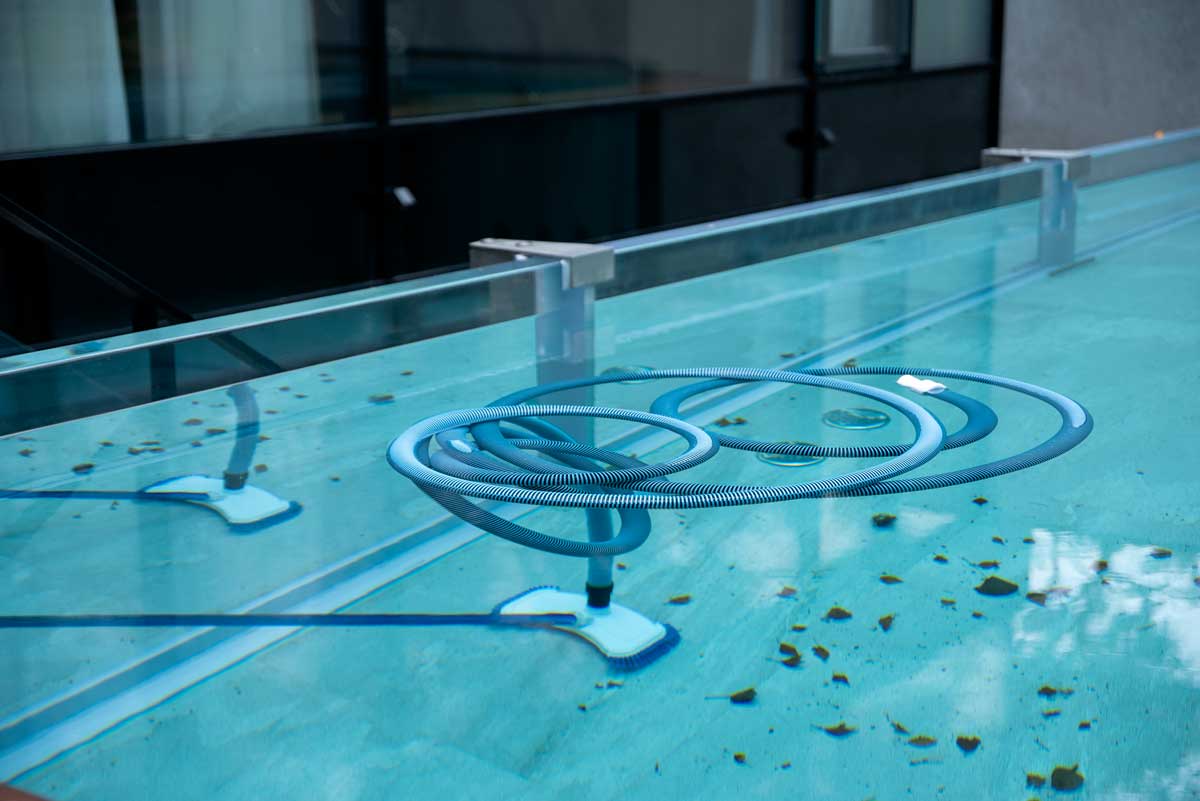Escoba de limpieza sumergida en el agua de la piscina exterior, para limpiar el fondo y las paredes, piscina llena de hojas y otros signos de abandono - suciedad