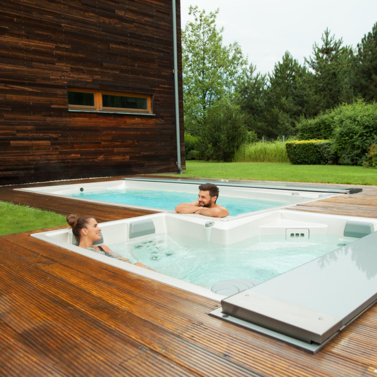 Pareja relajándose en el spa y la piscina de natación USSPA al aire libre instalados en una terraza de madera.
