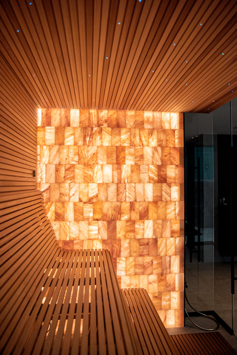 Pared de ladrillos de sal del Himalaya iluminada y techo de sauna estrellado.