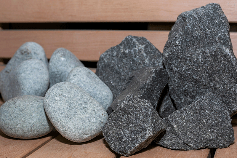 Comparación: piedras de río redondeadas y piedras de sauna partidas en un banco.