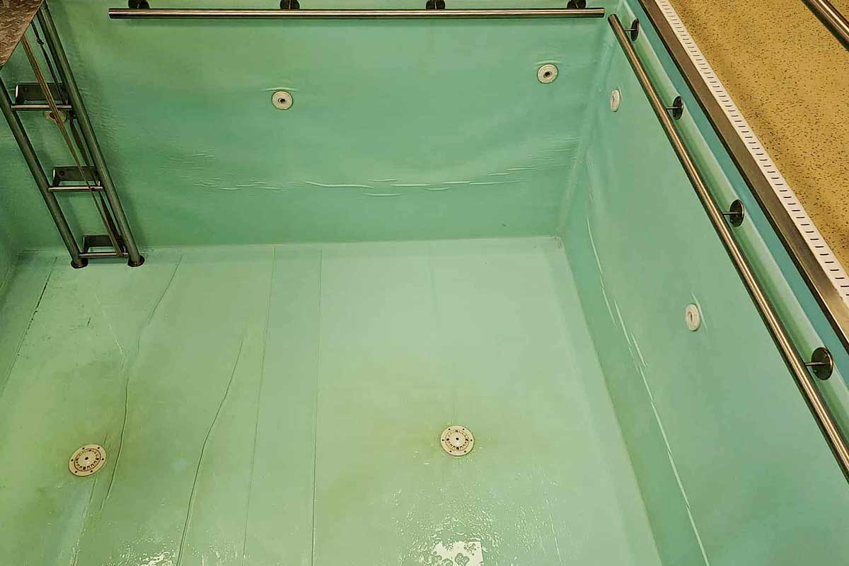 El fondo de la piscina está cubierto por una capa de algas verdes, el agua está turbia y da la impresión de un entorno descuidado y sucio.