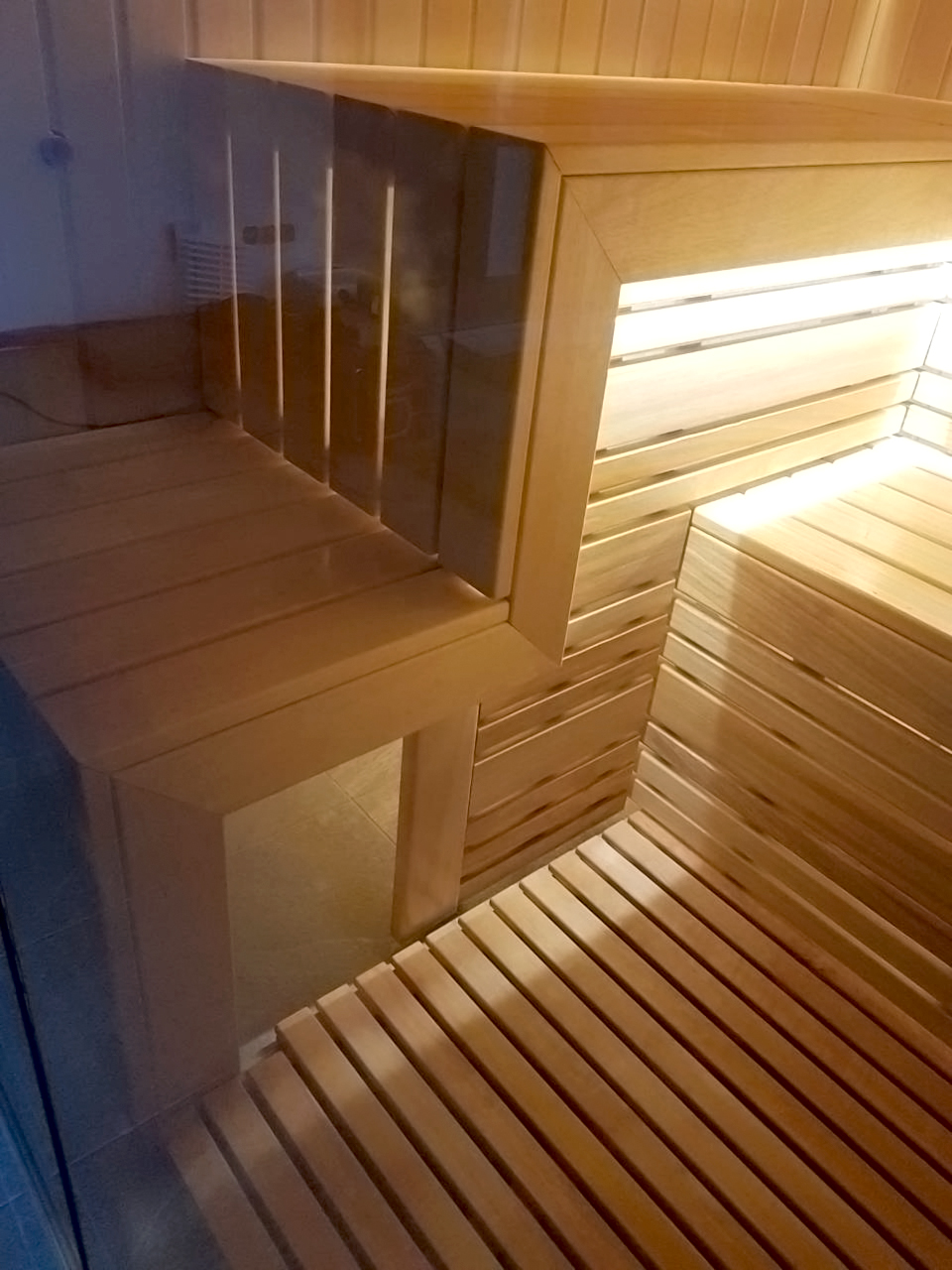 Sauna con fachada de cristal y vistas a la piscina.