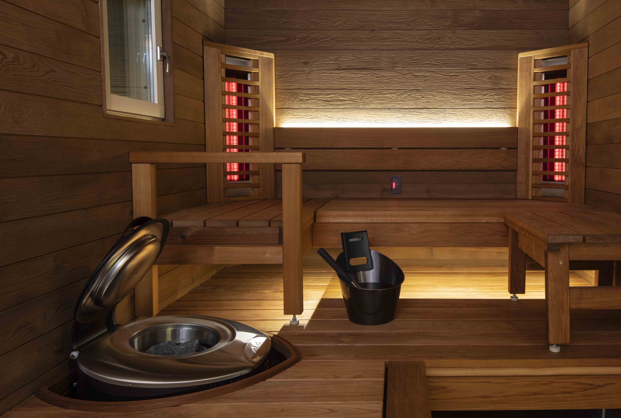 Interior de sauna de infrarrojos con bancos de madera, elementos calefactores y una estufa para la relajación y el bienestar.