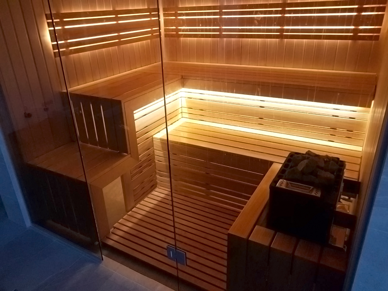 Sauna con fachada de cristal y vistas a la piscina.